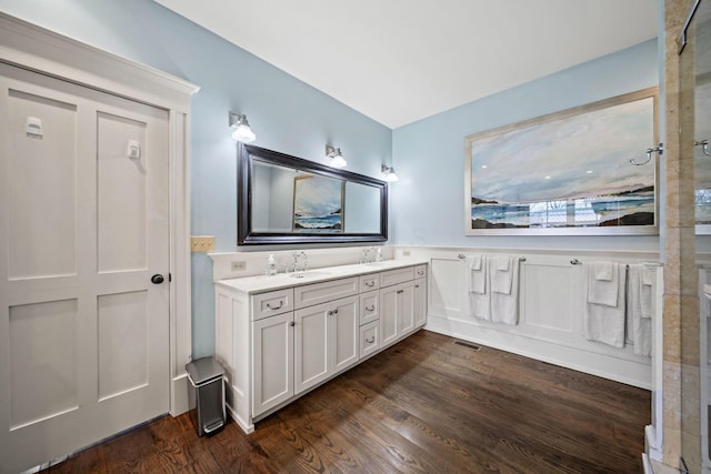 bathroom with wood finished floors, double vanity, a sink, and visible vents
