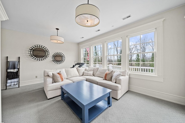 living area with visible vents, a wealth of natural light, carpet, and baseboards