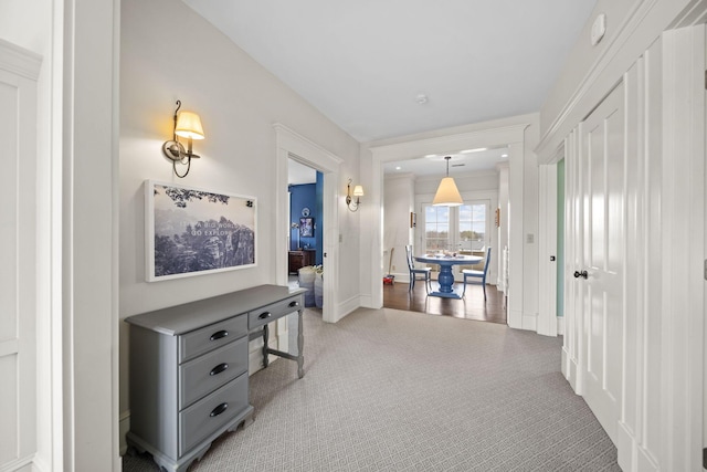 corridor featuring light colored carpet and baseboards