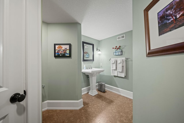 bathroom featuring visible vents, baseboards, and a textured ceiling