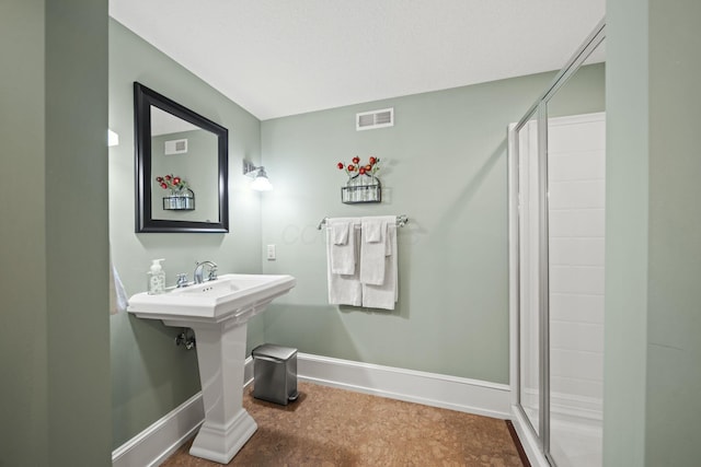 bathroom with a stall shower, baseboards, and visible vents