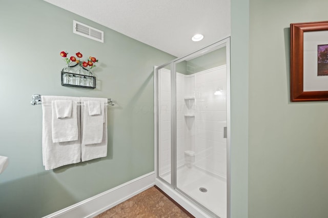 bathroom featuring a stall shower, baseboards, visible vents, and tile patterned floors