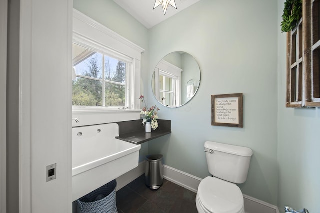 half bathroom featuring toilet, a sink, baseboards, and tile patterned flooring