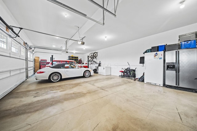 garage featuring freestanding refrigerator, stainless steel refrigerator with ice dispenser, and a garage door opener