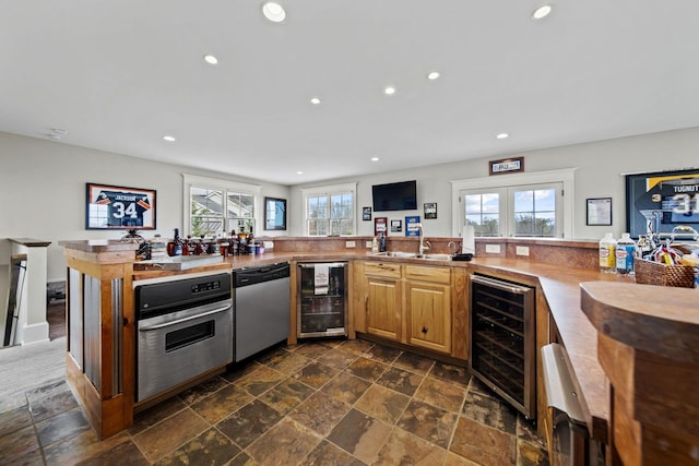 kitchen with stainless steel appliances, recessed lighting, stone tile floors, and beverage cooler