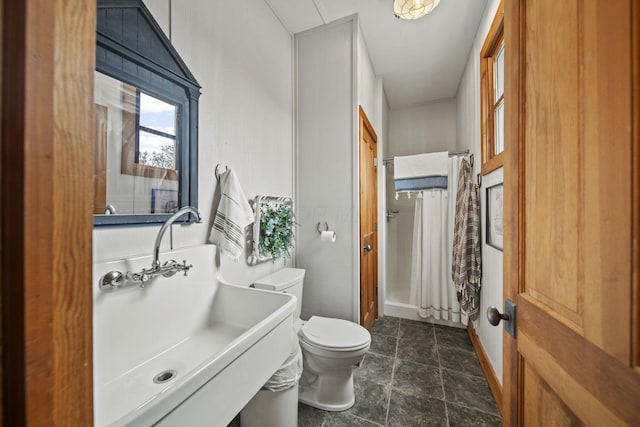bathroom with a sink, toilet, a shower with curtain, and stone finish flooring