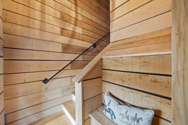 stairway featuring wooden walls