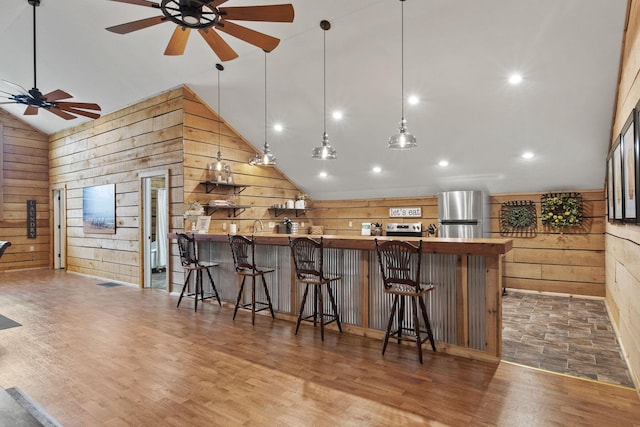 bar with high vaulted ceiling, freestanding refrigerator, a ceiling fan, wood finished floors, and wood walls