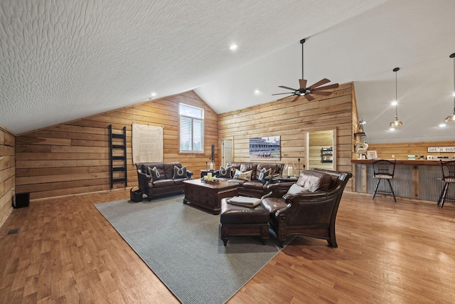 living room featuring wooden walls, wood finished floors, and vaulted ceiling