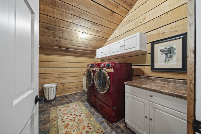 washroom with wooden walls, washing machine and dryer, cabinet space, stone finish flooring, and wooden ceiling