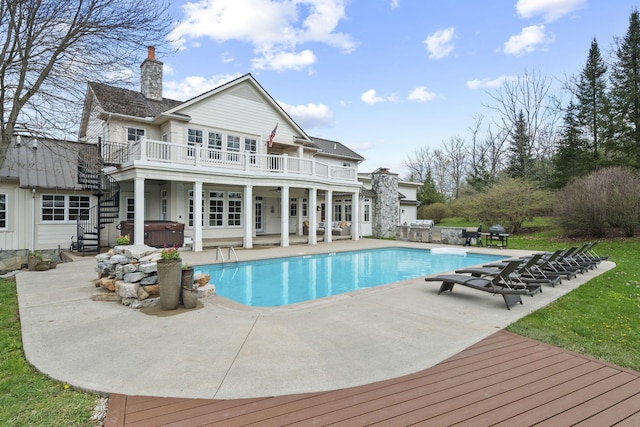 back of property featuring a patio area, a chimney, stairs, and a hot tub