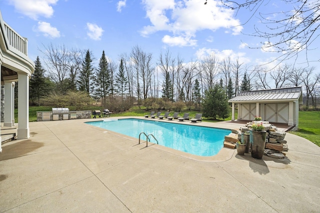 outdoor pool featuring an outbuilding, a patio area, and an outdoor kitchen