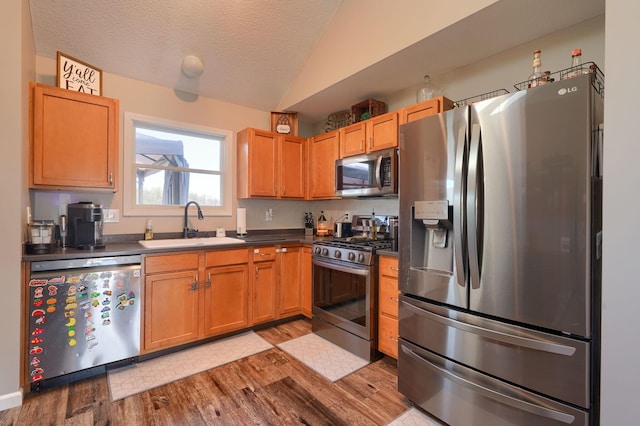 2655 Cross Creek Ave, Lancaster, OH 43130 - kitchen featuring a sink, dark countertops, stainless steel appliances, light wood-type flooring, and vaulted ceiling