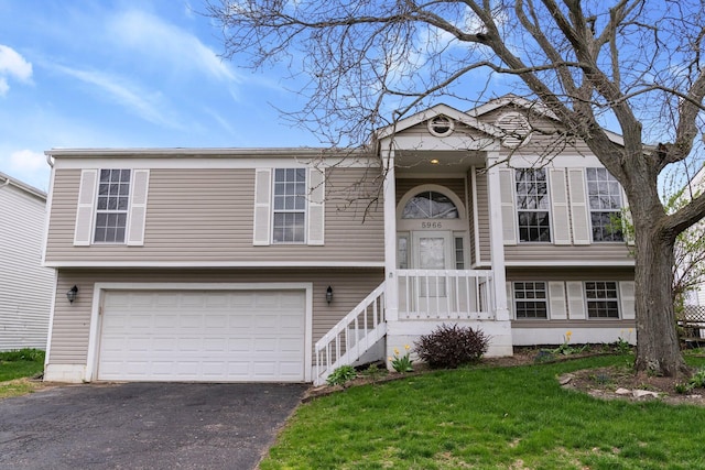 bi-level home with an attached garage, aphalt driveway, and a front yard