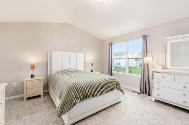 bedroom with baseboards, vaulted ceiling, visible vents, and light colored carpet