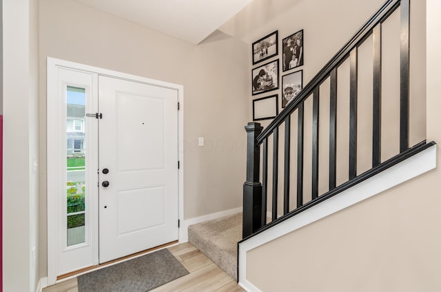 foyer entrance with baseboards, wood finished floors, and stairs
