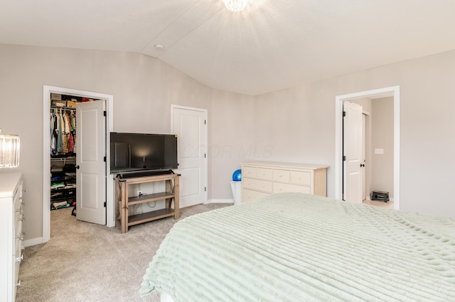 bedroom with vaulted ceiling, a closet, a spacious closet, light carpet, and baseboards