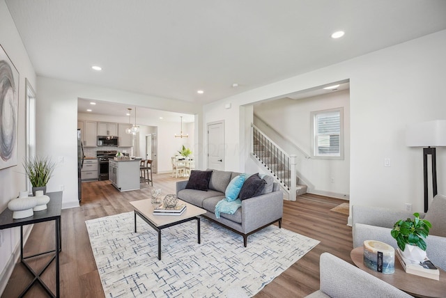 living area featuring recessed lighting, a chandelier, light wood-style floors, and stairs