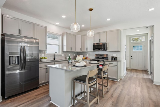 kitchen with light wood-style flooring, a sink, backsplash, and stainless steel appliances