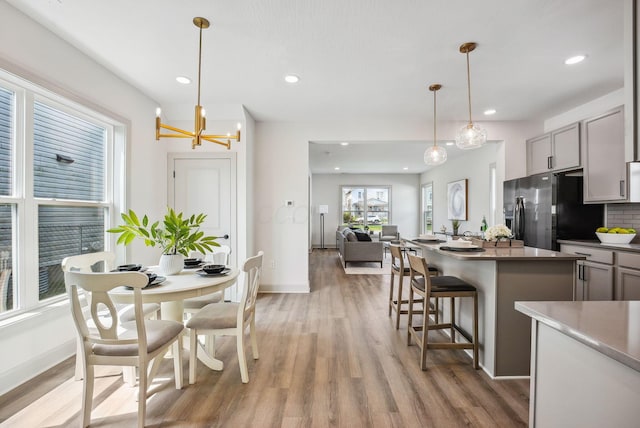 kitchen featuring light wood-style flooring, tasteful backsplash, baseboards, and stainless steel fridge