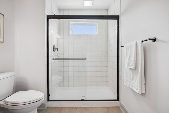 bathroom featuring toilet, a stall shower, and baseboards