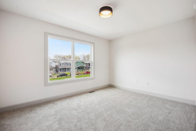 carpeted spare room featuring baseboards and visible vents