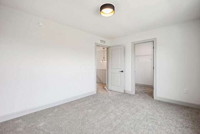 unfurnished bedroom with visible vents, a closet, baseboards, a spacious closet, and carpet