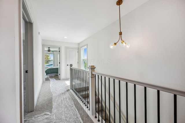 hall with light carpet and an inviting chandelier