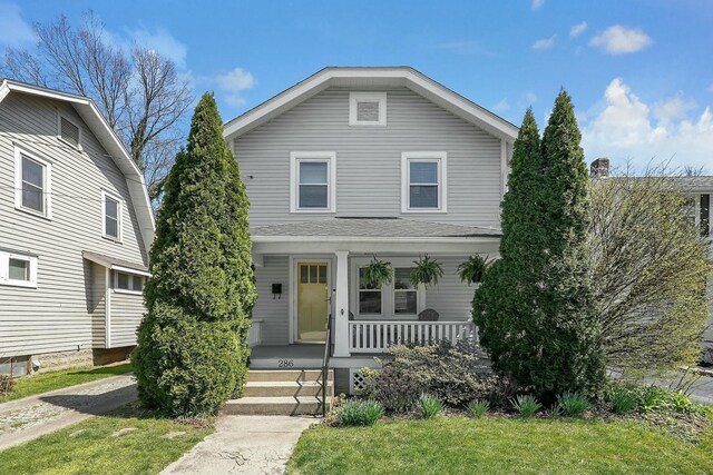 american foursquare style home with a front yard and covered porch