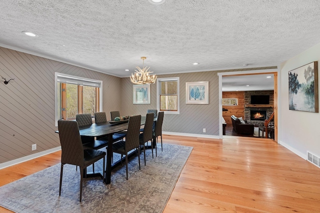 19990 Sowers Rd, Laurelville, OH 43135 - dining area with wood finished floors, an inviting chandelier, a fireplace, baseboards, and a textured ceiling