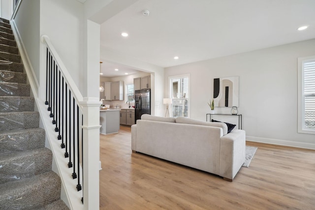 living room featuring stairway, a healthy amount of sunlight, and light wood-type flooring