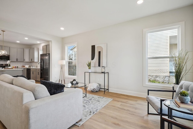 living area with light wood-style flooring, baseboards, and recessed lighting