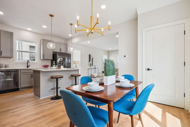 dining room featuring light wood finished floors, recessed lighting, and a notable chandelier
