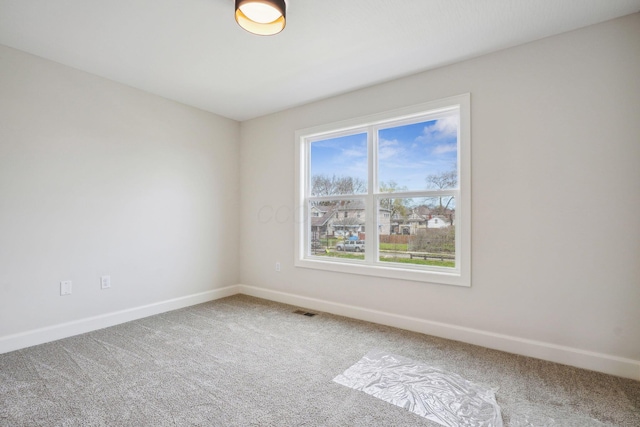 carpeted spare room featuring baseboards and visible vents