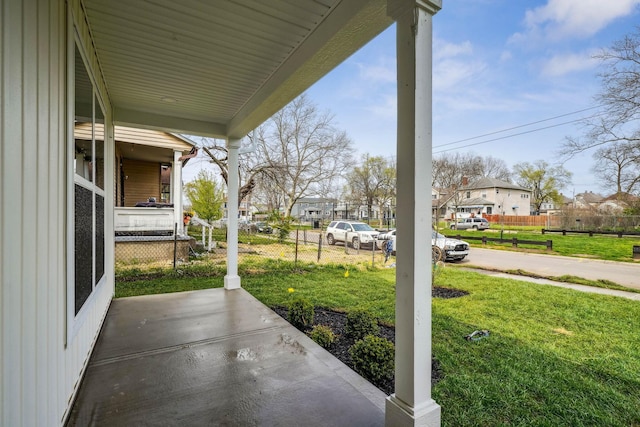 view of patio / terrace featuring fence, a residential view, and covered porch