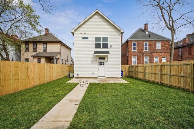 rear view of house featuring a lawn, a fenced backyard, and a patio