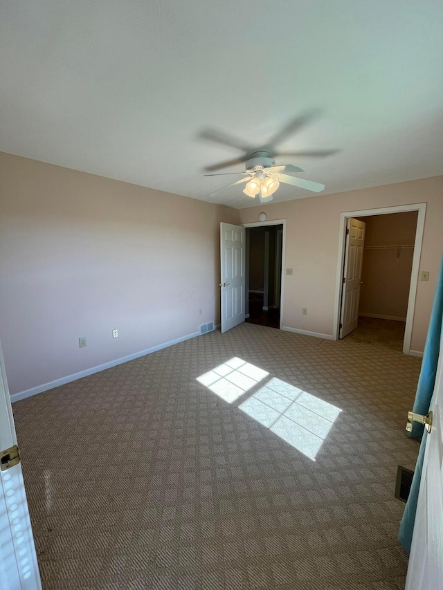 unfurnished bedroom featuring a spacious closet, carpet flooring, visible vents, and baseboards