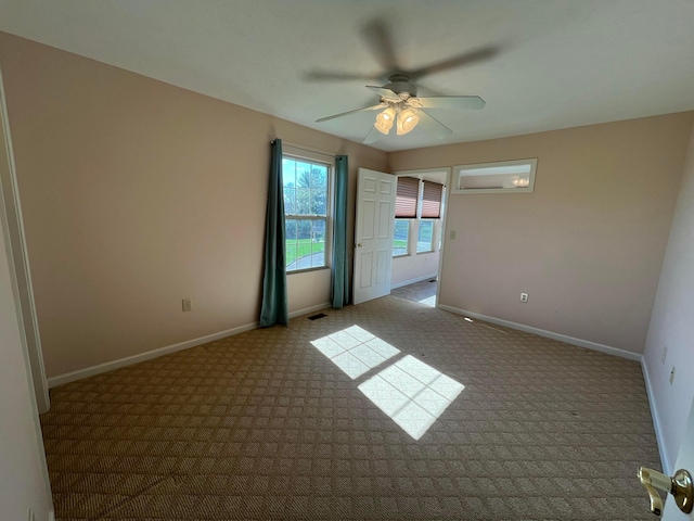 carpeted empty room with ceiling fan, baseboards, and visible vents