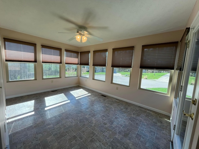 unfurnished sunroom with visible vents, baseboards, and a wealth of natural light
