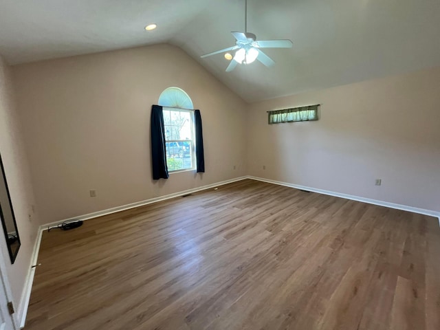 spare room with wood finished floors, baseboards, a ceiling fan, and vaulted ceiling