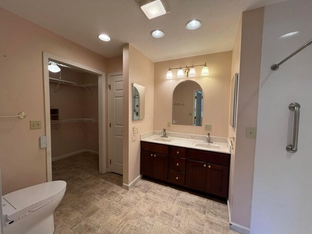 bathroom featuring recessed lighting, double vanity, a sink, and toilet