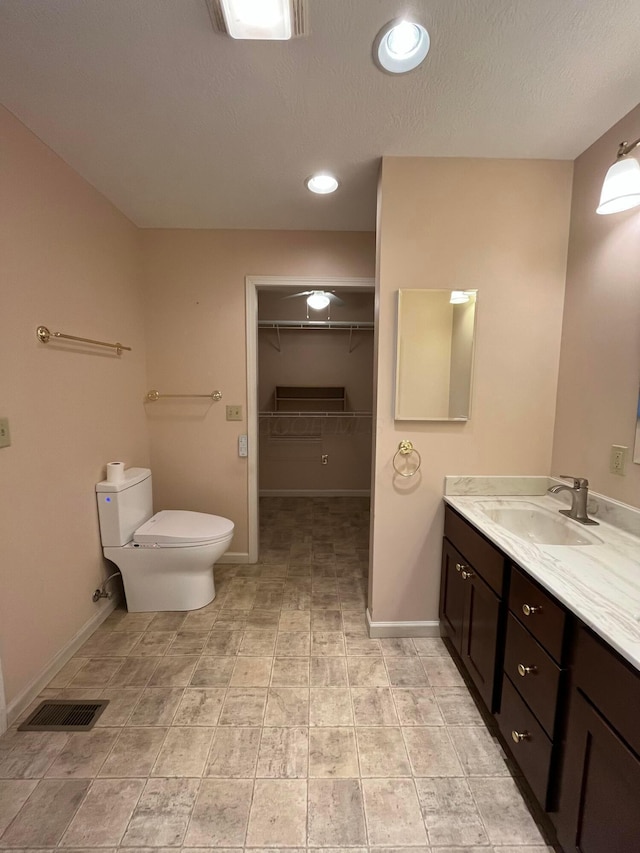bathroom with vanity, visible vents, baseboards, and toilet