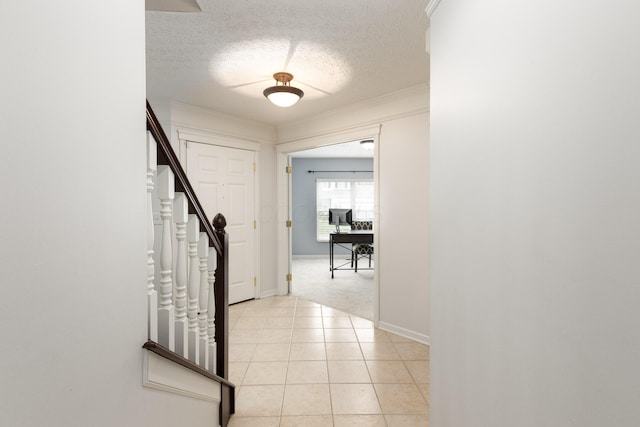 hall with stairs, an office area, a textured ceiling, light tile patterned flooring, and baseboards