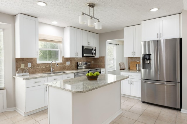 kitchen featuring appliances with stainless steel finishes, a sink, white cabinetry, plenty of natural light, and a textured ceiling