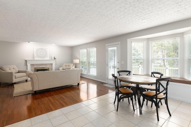dining room featuring a textured ceiling, a tile fireplace, tile patterned flooring, and baseboards