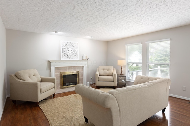 living room featuring dark wood-style flooring, a fireplace, and a textured ceiling