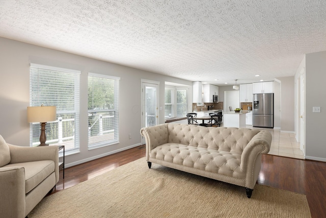 living area featuring light wood-style floors, baseboards, a textured ceiling, and recessed lighting