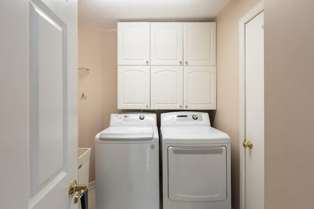 clothes washing area with independent washer and dryer, cabinet space, and a textured ceiling