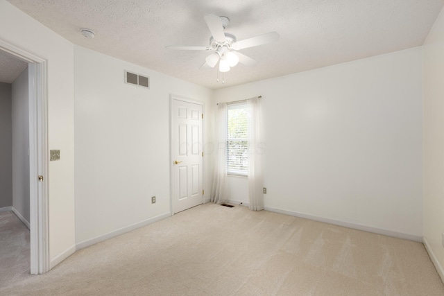 empty room with light carpet, ceiling fan, a textured ceiling, baseboards, and a smoke detector