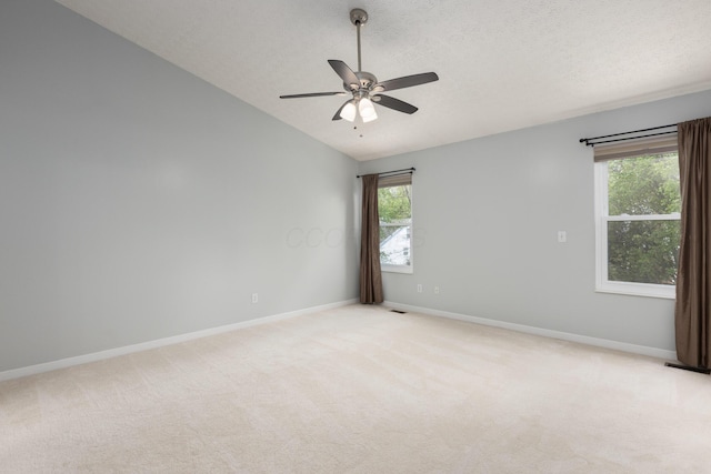 unfurnished room featuring lofted ceiling, plenty of natural light, ceiling fan, baseboards, and light carpet